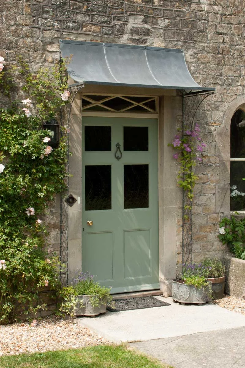 An aged zinc metal scooped porch with supporting metal latticework columns