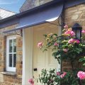 Aged zinc galvanized steel door canopy with roses over front door in UK