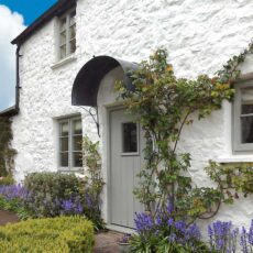 A door canopy in aged zinc shown above the front door of a country cottage