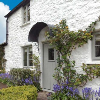 A door canopy in aged zinc shown above the front door of a country cottage