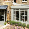 Large aged zinc galvanized metal canopy over painted patio doors on London brick house in UK