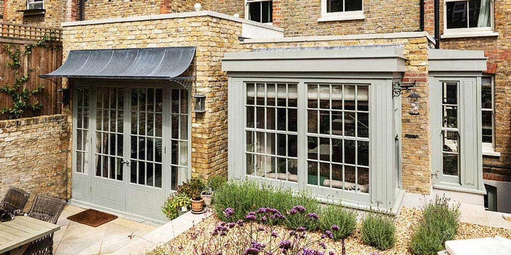 Large aged zinc galvanized metal canopy over painted patio doors on London brick house in UK