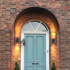 Roman door canopy in galvanised steel set above a front door with fanlight.