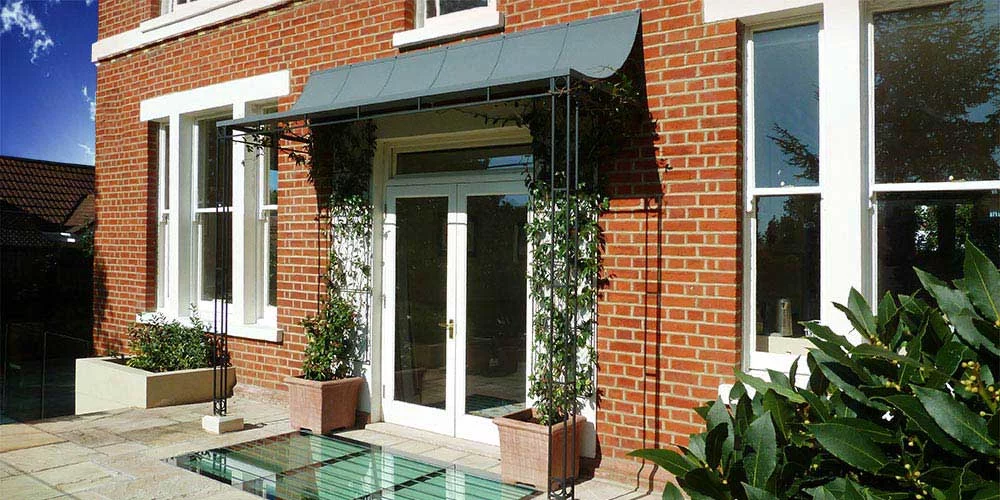 Large wrought iron porch with zinc roof above French doors