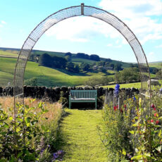 Wirework Roman Arch frames a garden path and bench