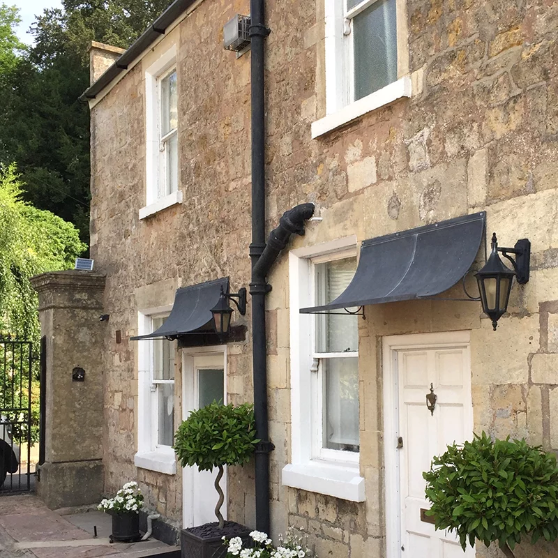 Wrought iron door canopies in UK above side doors with bay trees