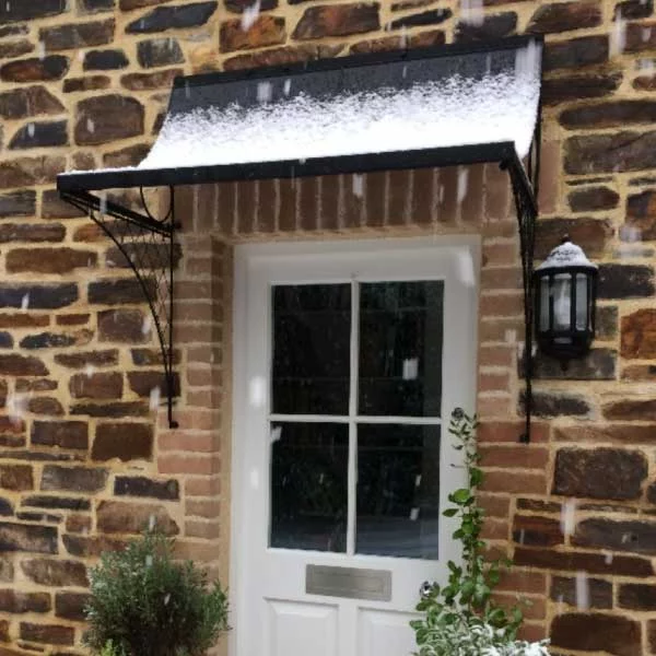 A zinc metal front door canopy covered with snow