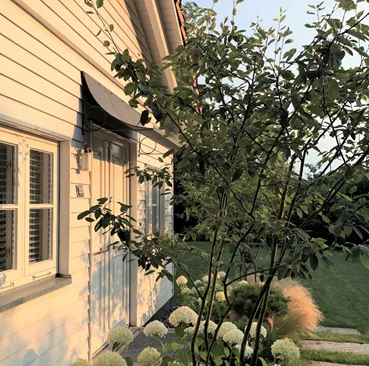 Metal door canopy over French doors on timber clad house