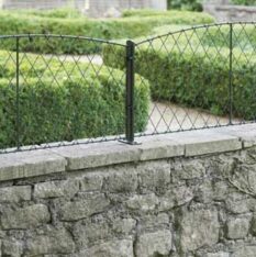 wall-top=trellis-panels a low garden wall capped with wall top trellis panels in black wire with metal supporting posts