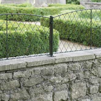 a low garden wall capped with wall top trellis panels in black wire with metal supporting posts