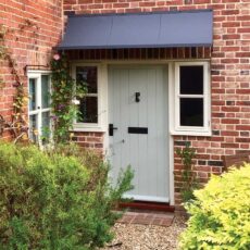 A dark grey zinc metal canopy set above a traditional front door