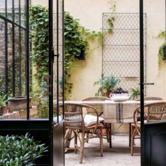 A courtyard garden with zinc metal English wire work wall trellis panels and climbing plants.