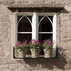 a small wire work window box holding three flowering plants