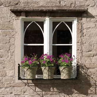 a small wire work window box holding three flowering plants
